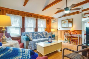 Ein gemütliches Zimmer mit einer Couch, einem Couchtisch, einem Esstisch mit Stühlen und einem Deckenventilator.