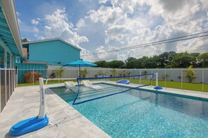 A swimming pool with a blue net, a covered area, and a covered structure.
