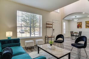 Uma sala de estar moderna com um sofá verde-água, uma mesa de centro e um espaço de jantar com cadeiras e uma mesa.