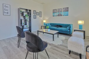 Una sala de estar moderna con un sofá, dos sillones, una mesa de centro y una estantería.