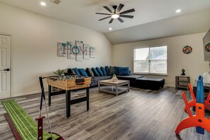 A living room with a foosball table, a sofa, a coffee table, and a ceiling fan.