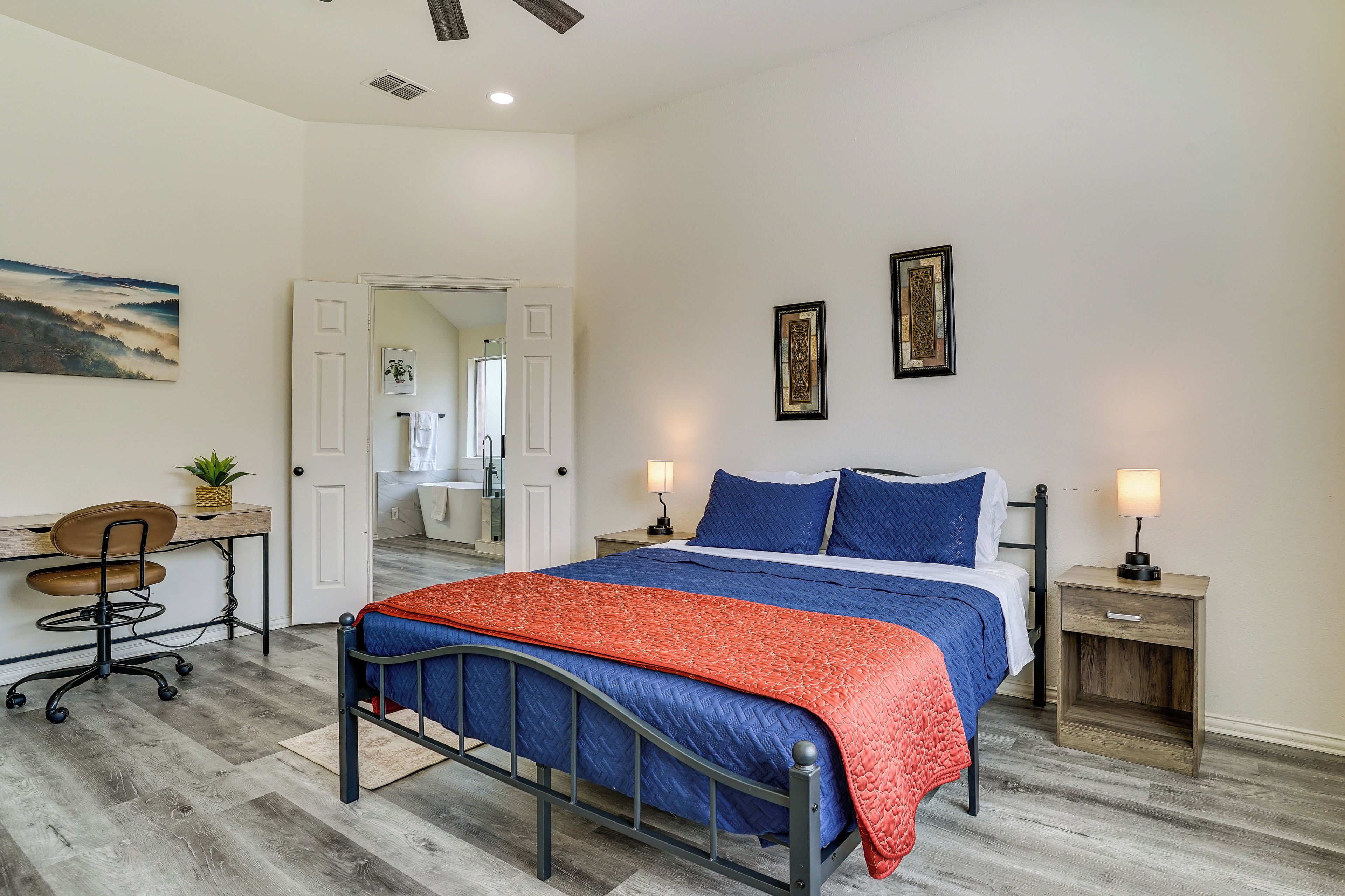 A bedroom with a bed, bedside tables, a desk, and a chair.