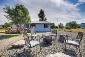 A rustic cabin with a gravel patio, outdoor seating, and a fire pit.