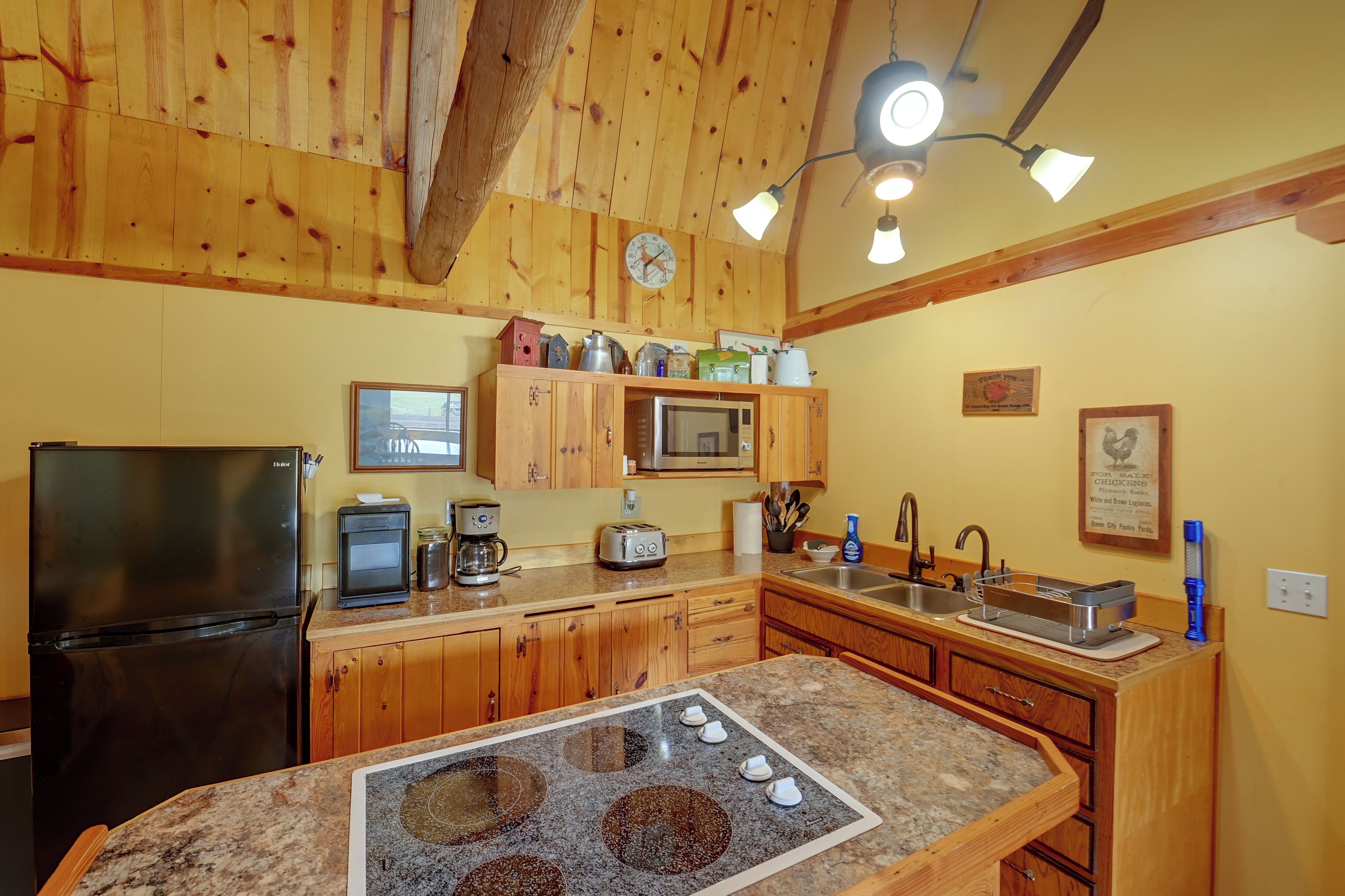 A kitchen with wooden cabinets, a refrigerator, a microwave, a toaster, and a coffee maker.