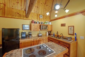 Una cucina con mobili in legno, un frigorifero, un forno a microonde, un tostapane e una macchina da caffè.