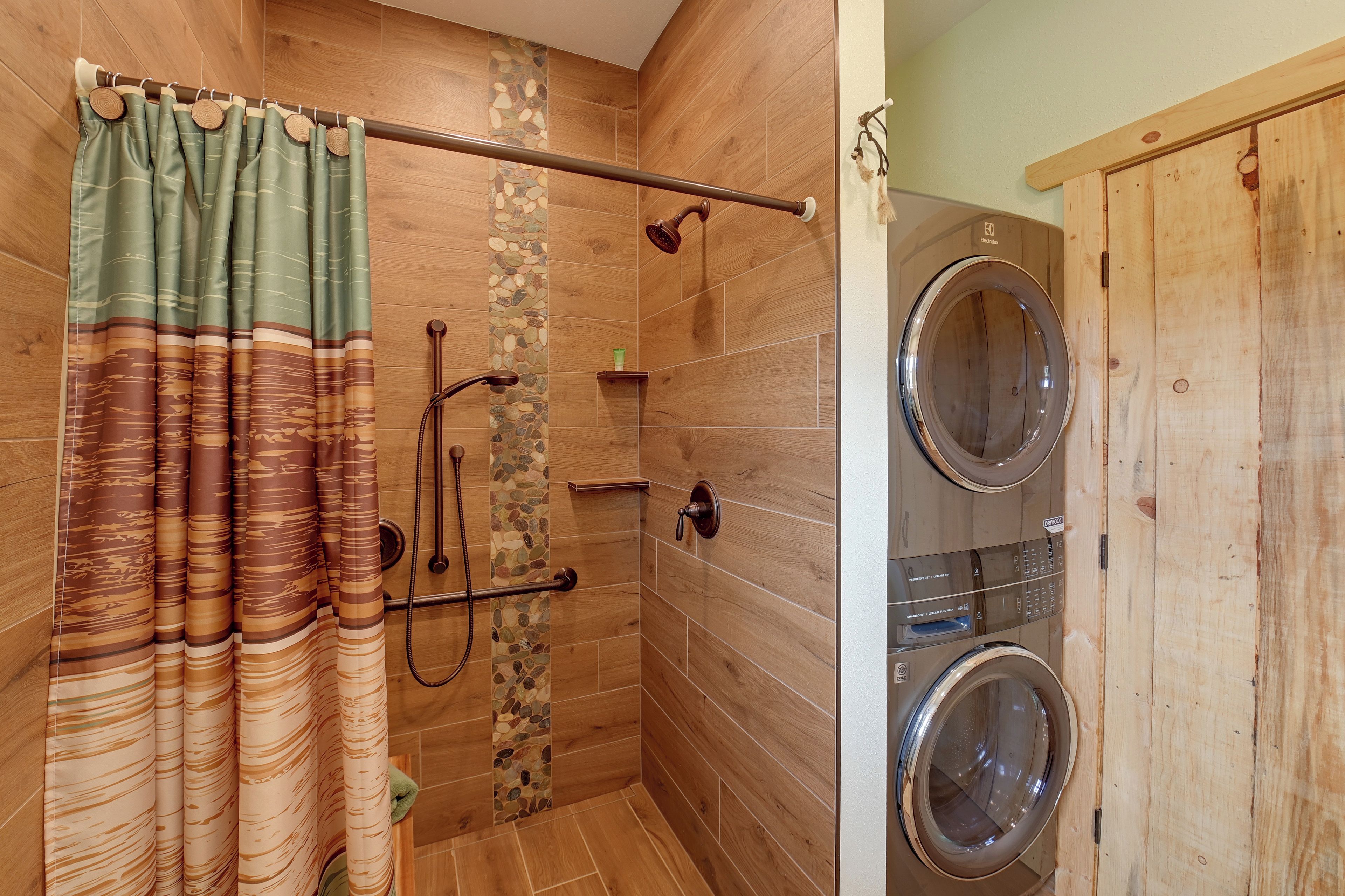 A shower area with a wooden wall, a shower curtain, and a built-in washing machine.