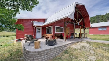A red barn with a covered porch, a brick wall, and outdoor seating.