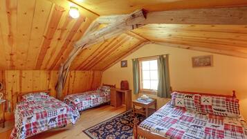 Una cabaña acogedora con dos camas de madera, una mesita y una ventana con cortinas.