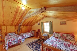 Uma cabana acolhedora com duas camas de madeira, uma mesa pequena e uma janela com cortinas.