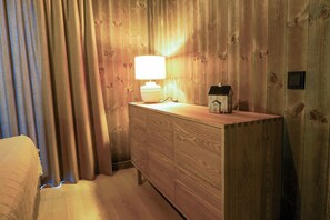 A wooden dresser with a lamp and a house-shaped object on top.