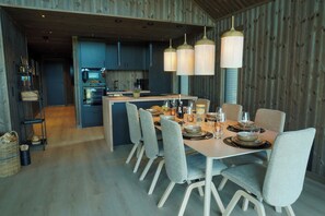 Une cuisine moderne dotée d’un îlot central, d’une table à manger avec des chaises et d’un éclairage suspendu.