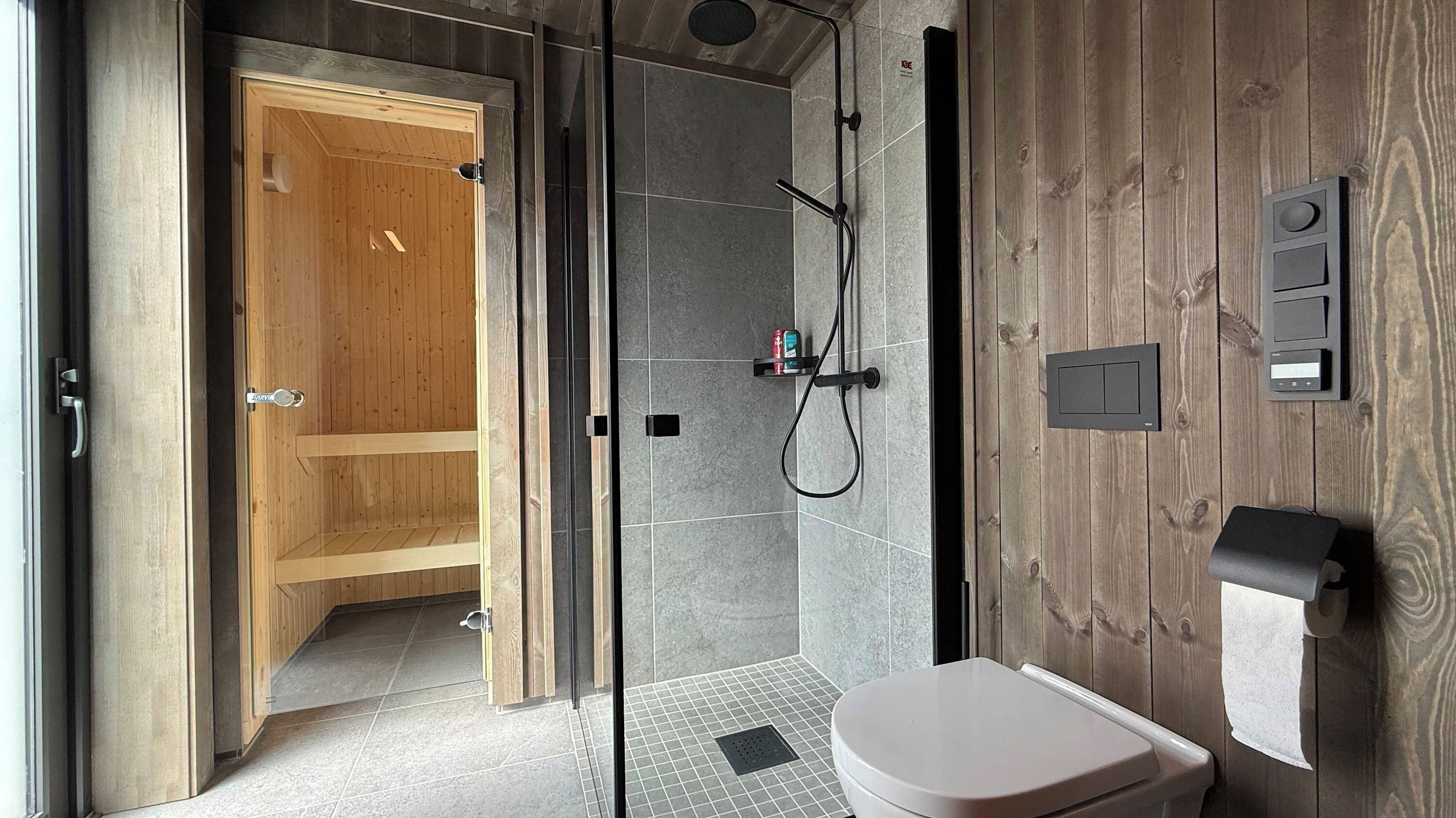 A modern bathroom with a glass-enclosed shower, a wooden vanity, and a toilet.