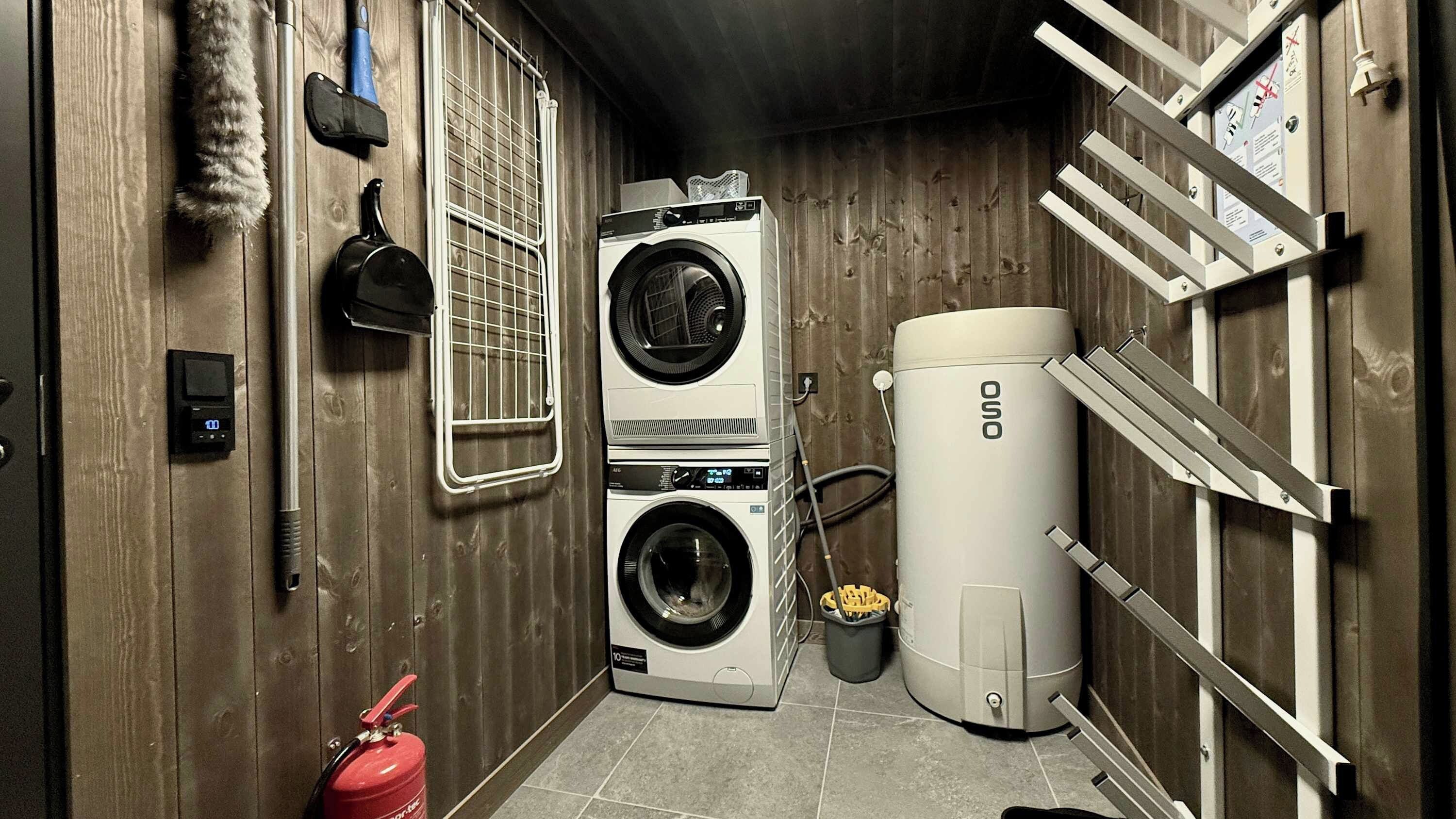 A laundry room with two washing machines, a dryer, a fire extinguisher, and a water heater.