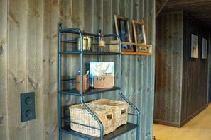 A metal shelving unit with wicker baskets and decorative items against a wooden wall.