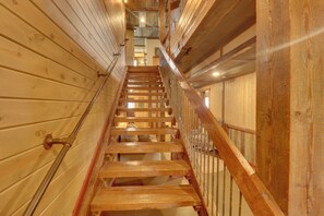 Una escalera de madera con barandillas de metal que sube a un nivel superior.