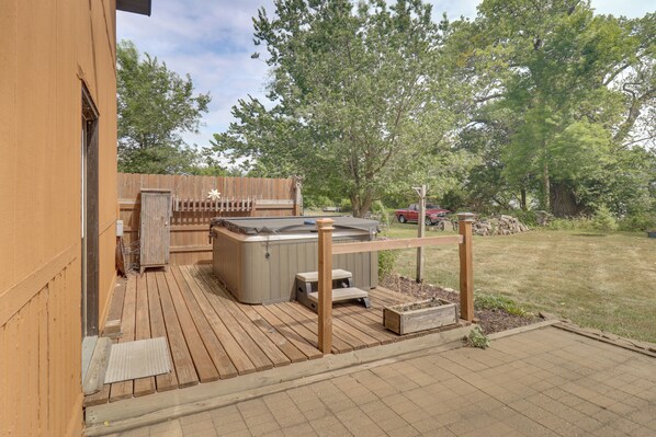 Una terraza de madera con un jacuzzi, una valla de madera y un patio cubierto.