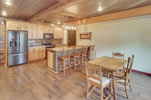 Una cocina amplia con armarios de madera, electrodomésticos de acero inoxidable y un comedor con sillas y mesa de madera.