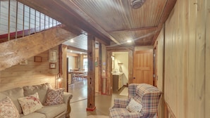 Un interior acogedor con una escalera de madera, un sofá, un sillón a cuadros y un comedor.