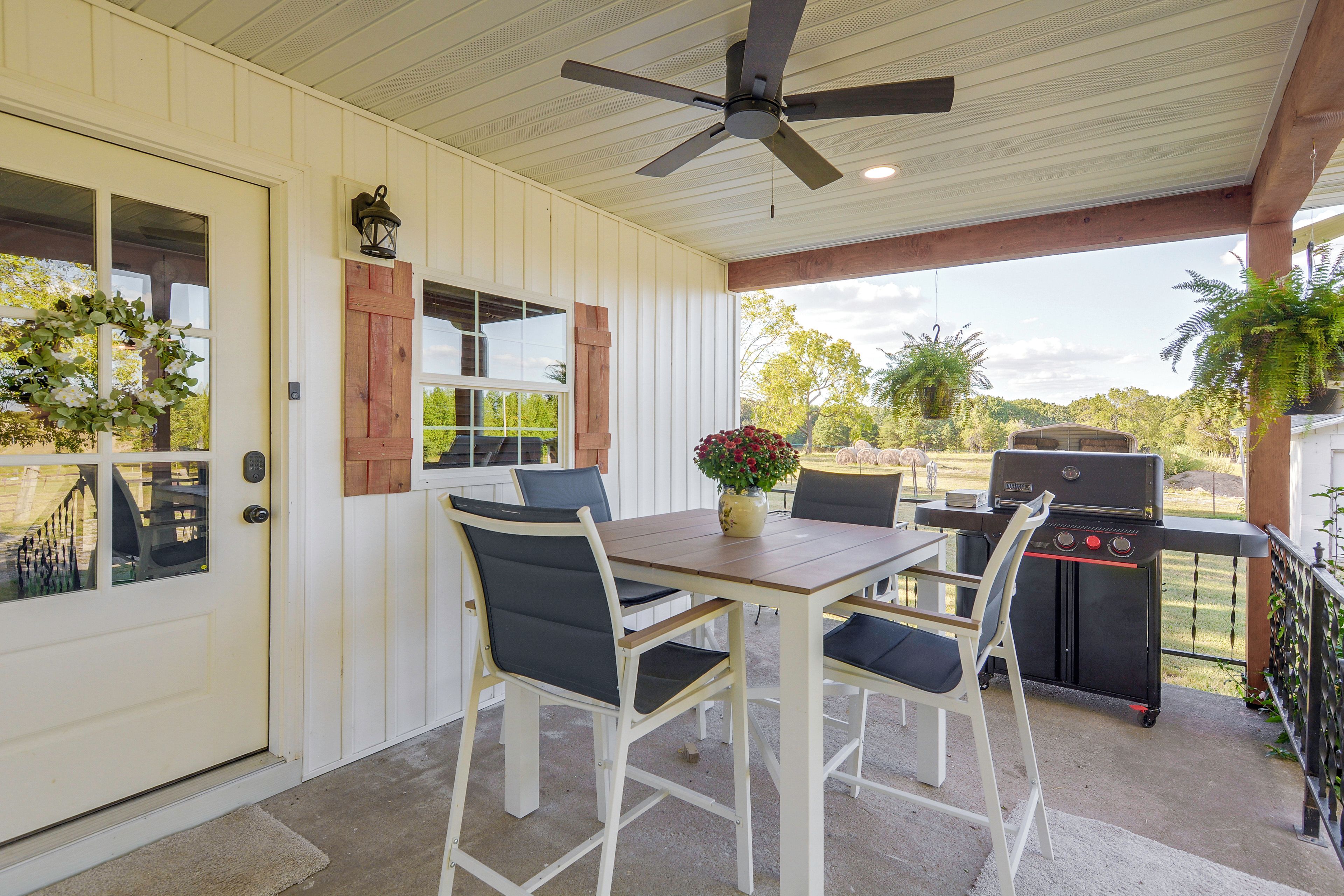 Eine Terrassengastronomie mit Tisch, Stühlen, Deckenventilator und Grill.