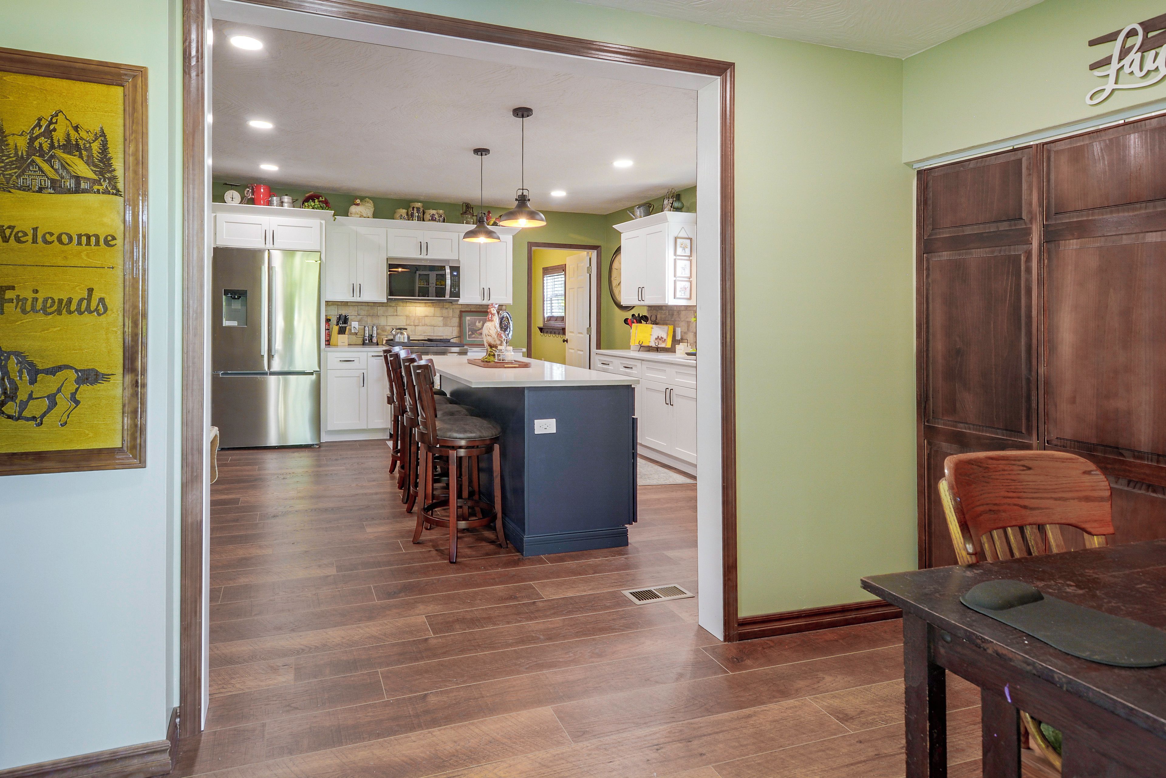 Una cocina con una isla central, sillas de madera y una mesa de comedor.