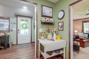 A hallway with a white door, a clock, and a shelf with kitchen utensils. - Country Living! Fire Pit, Horse Stalls & Views (Verona)