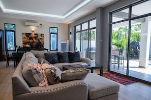 Una sala de estar moderna con un sofá modular, un comedor y grandes puertas correderas de vidrio que dan a un patio exterior.