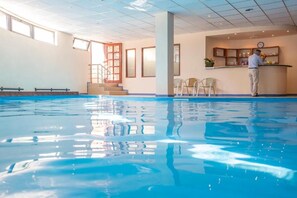 An indoor swimming pool with clear water, a reception desk, and a staircase leading to an upper level. - Kaliakra Palace (Varna)