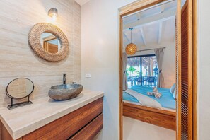A modern bathroom with a stone sink, wooden vanity, and a large mirror. - Your private Aruba escape with nearly everything brand new, 4 bedrooms, a tropical pool, waterfall wish spot, BBQ, and easy access to Palm Beach. (Noord)