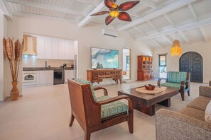 A spacious living area with a dining table, two chairs, a television, and a kitchen in the background. - Your private Aruba escape with nearly everything brand new, 4 bedrooms, a tropical pool, waterfall wish spot, BBQ, and easy access to Palm Beach. (Noord)