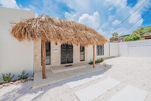 A building with a thatched roof, a stone pathway leading to the entrance, and a sign indicating the name 'Luda'. - Your private Aruba escape with nearly everything brand new, 4 bedrooms, a tropical pool, waterfall wish spot, BBQ, and easy access to Palm Beach. (Noord)