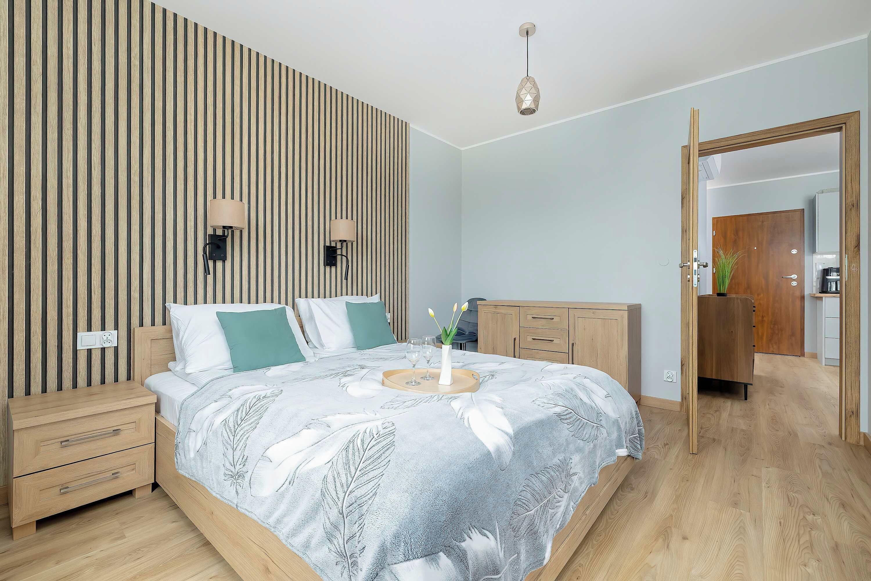 Quarto moderno com cama, mesas de cabeceira, cômoda e guarda-roupa de madeira.