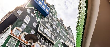Een meerhoog gebouw met een opvallend architectuurontwerp, met een combinatie van groene en blauwe gevels en een prominente witte afwerking.