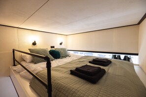 Ein Einzelbett mit Kopfteil, ein Nachttisch und ein Fenster mit Blick ins Freie.