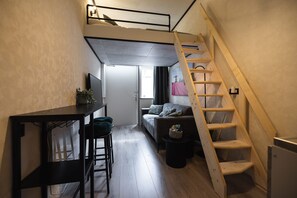 Ein kompakter Wohnraum mit Schlafkoje, Schreibtisch und einer Couch.