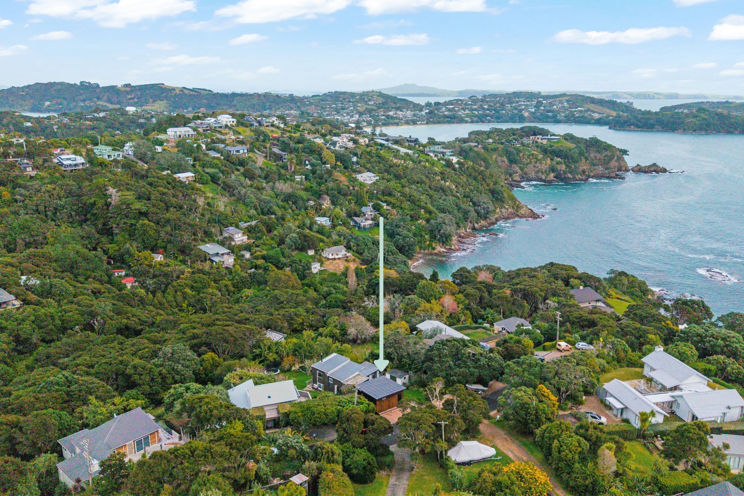Ein Küstenwohngebiet mit Häusern, umgeben von üppiger Vegetation und freiem Blick auf das Meer.