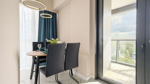 A modern dining area with a table set for two, a view of the city through a large window, and a balcony with a view of the cityscape. - Apartamenty Sun & Snow Hanza Tower (Szczecin)
