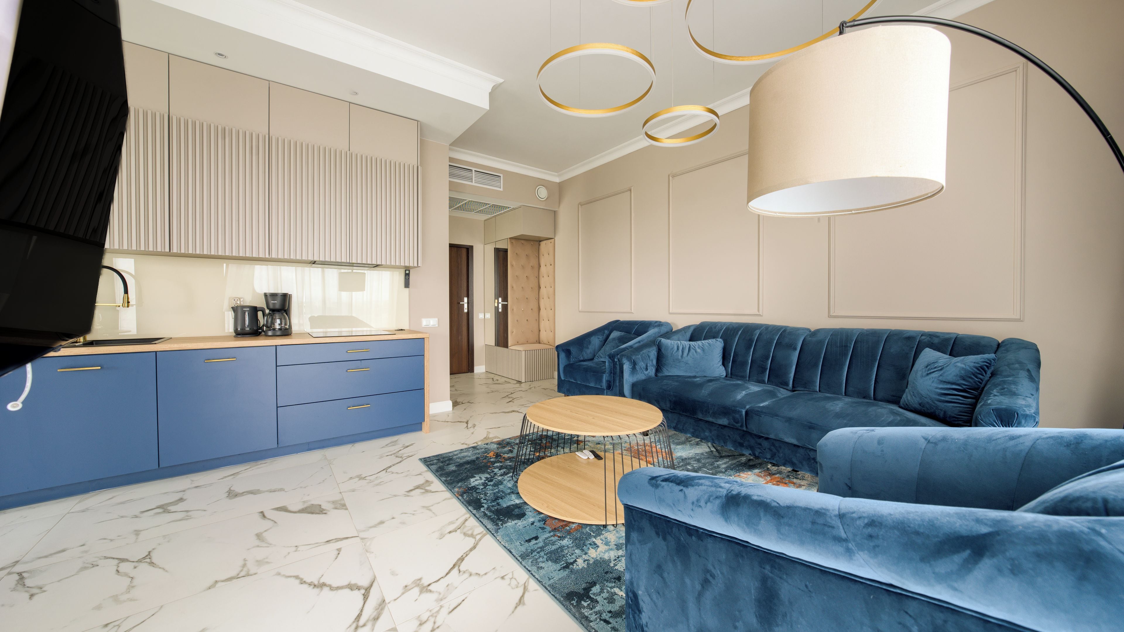 Una sala moderna con un sofá azul, una mesa de centro y una zona de cocina con armarios azules.