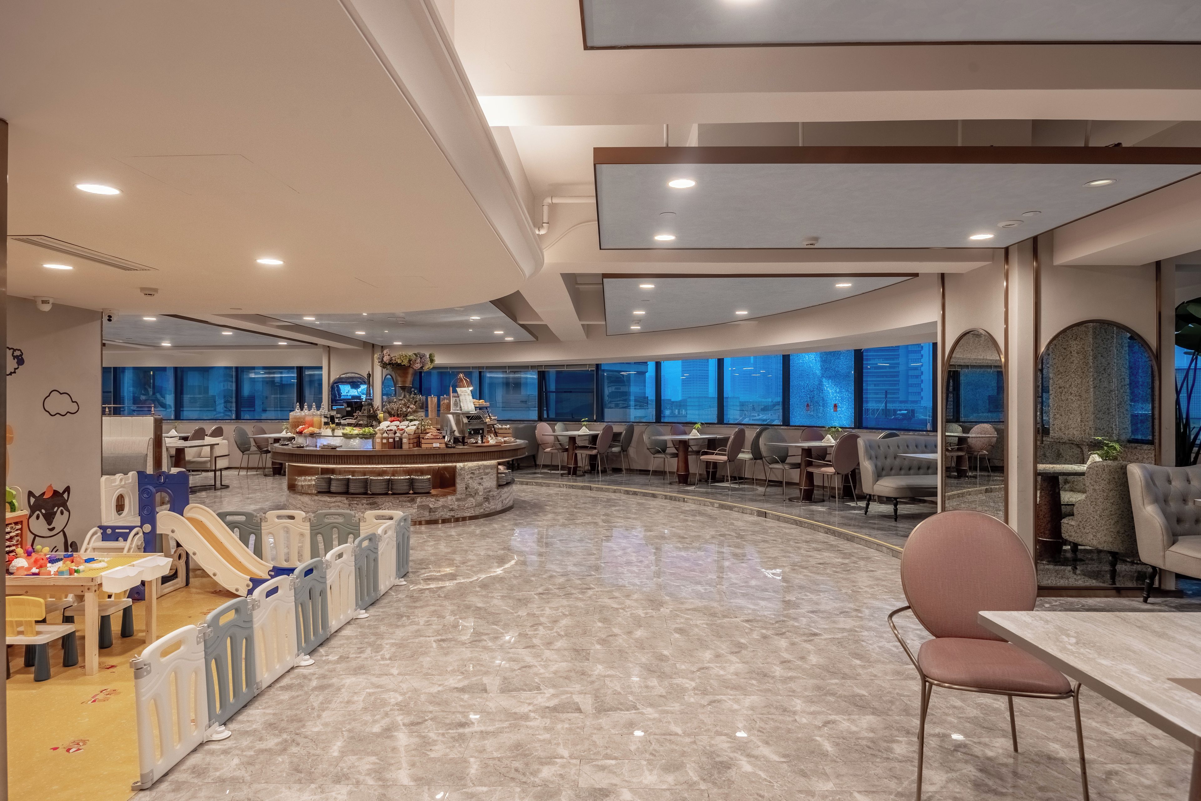 A spacious indoor area with a children's play area, a central bar, and seating arrangements.