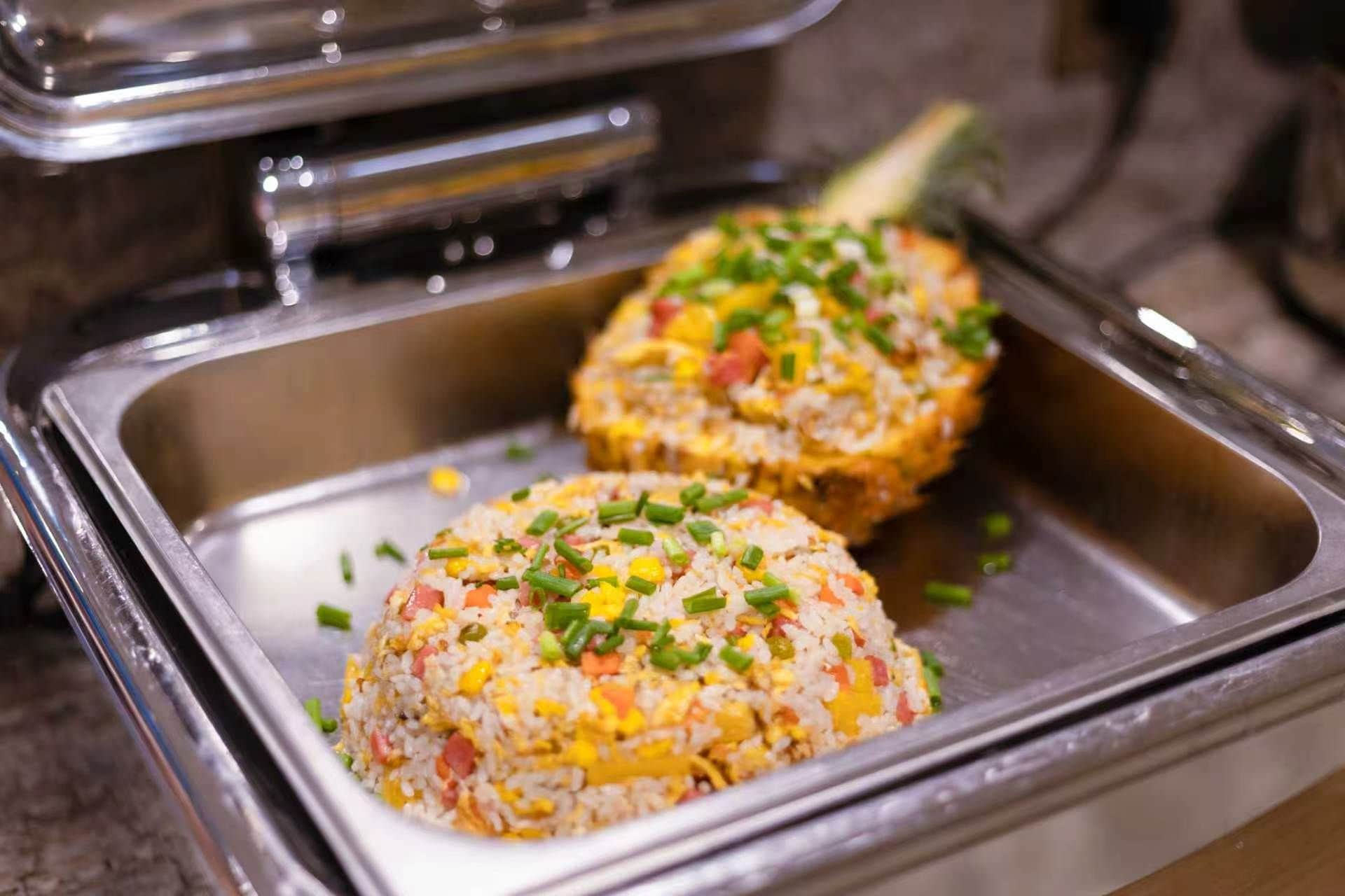 A buffet with two dishes of fried rice garnished with green onions.