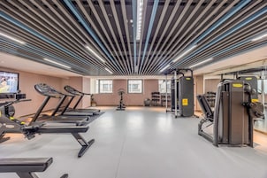 Un gimnasio con cintas de correr, bicicletas estáticas y máquinas de pesas.