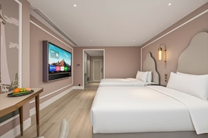 Una habitación de hotel con cama, mesita de noche, televisión y una lámpara fijada a la pared.