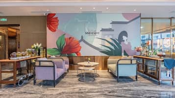 Un hall de hotel con zonas de estar, mostrador de recepción y un gran mural en la pared.