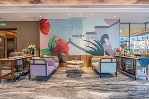 A hotel lobby with seating areas, a reception desk, and a large wall mural.