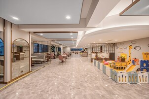 A spacious children's play area with a slide, play tables, and seating.