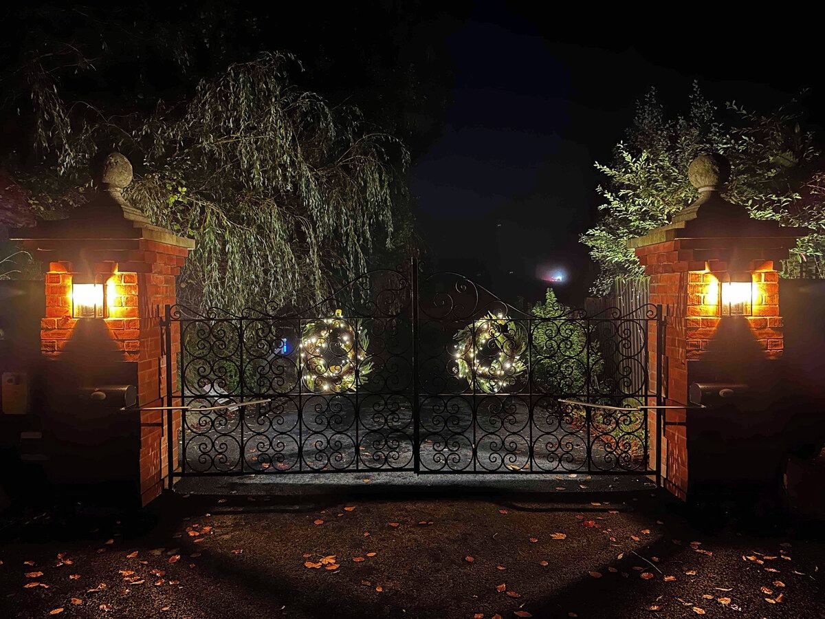 A gated entrance with decorative lights and a brick wall.