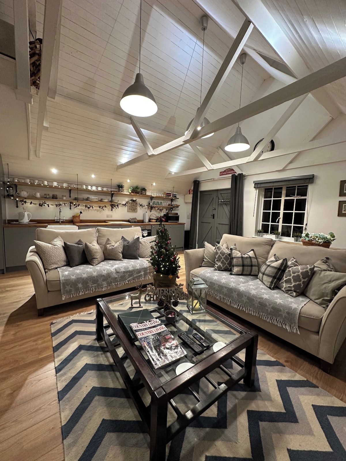 A spacious living room with two sofas, a coffee table, and a kitchen in the background.