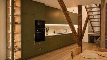 Een moderne keuken met inbouwapparatuur, een houten eettafel en een trap.