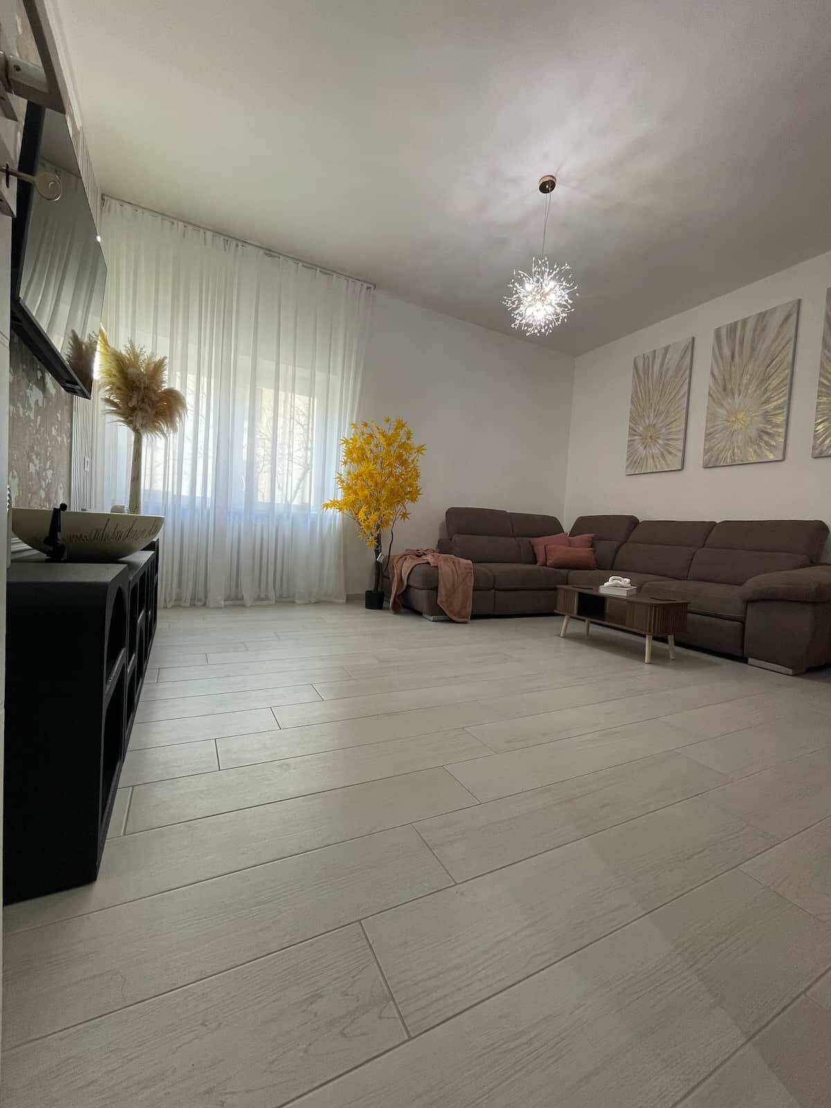 Ein Wohnzimmer mit einer Couch, einem Couchtisch, einer Zimmerpflanze und einer modernen Lampe.