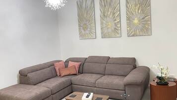 Un salon moderne avec un canapé d’angle, une table basse et des œuvres d’art décoratives au mur.