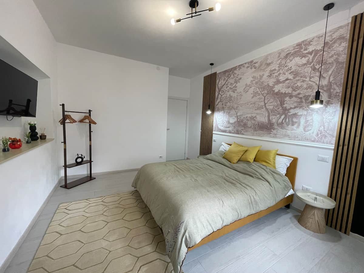 Un dormitorio moderno con cama, mesita de noche, estante montado en la pared y alfombra con diseño geométrico.
